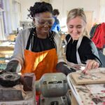 Two workshop visitors using a buffing wheel.